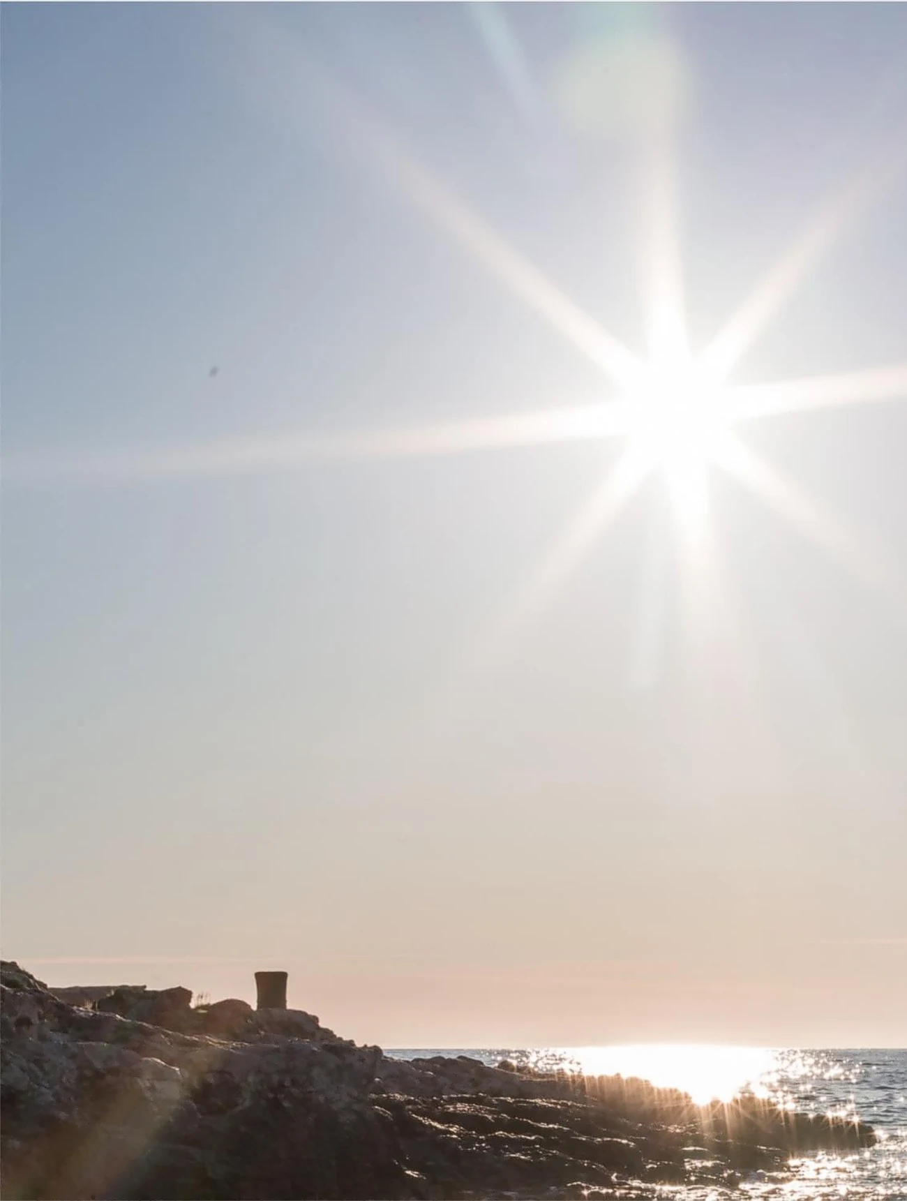 A star of sunlight over a rocky shore